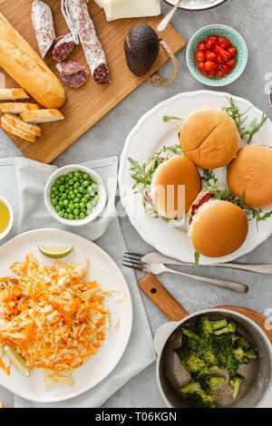 Hohe Betrachtungswinkel der Sommer Party Food Konzept. Vegetarische Burger mit verschiedenen Lebensmitteln. Vegetarische Kost ist nicht nur. Verschiedene Lebensmittel auf dem Tisch flach Stockfoto