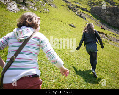 Zwei Mädchen im Teenager-Alter, die an der Seite eines Hügels, Peak District, Dovedale, Großbritannien Stockfoto