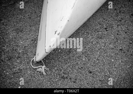 Kajak aus weißem Fiberglas Kunststoff mit im Alter von Marken mit weißen Kordel am Strand mit schwarzem Sand und Steine am Meer mit keine Menschen, Hintergrund wit Stockfoto