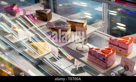 Ein Fenster in einer Bäckerei mit vielen Kuchen und Desserts, ein Spiegelbild von Lichtern, Schokolade, napoleon, samt Stockfoto