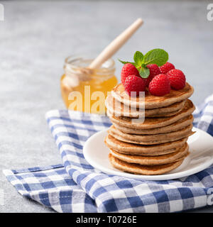 Ganze Weizen Pfannkuchen mit Himbeeren und Honig an der Platte. Detailansicht, Quadrat Erntegut Stockfoto