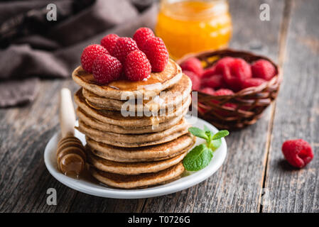 Pfannkuchen mit Himbeeren und Honig auf Holztisch. Stapel von Weizen Pfannkuchen. Leckeres Frühstück, rustikal essen Fotografie Stockfoto