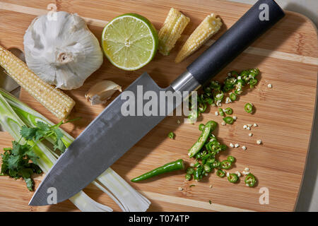 Asiatische Thai Chilis und Gemüse Zutaten auf Schneidebrett mit Santoku Messer Stockfoto