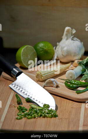 Asiatische Thai Chilis und Gemüse Zutaten auf Schneidebrett mit Santoku Messer Stockfoto