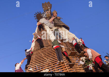 Männer, gekleidet in der Tracht der Arbeit an großen Modell der Virgen de los Desamparados (Unsere Dame der Verlassenen) und bedeckte ihn mit Blumen während Las Fallas Festival in Valencia. Fallas sind riesige Skulpturen von berühmten Persönlichkeiten oder aktuelle Ereignisse in den Straßen von Valencia, die gesehen werden können, während das "Las Fallas" Festival, das Skulpturen werden dann am 19. März 2019 zu Ehren des heiligen Joseph, Schutzpatron der Zunft der Zimmerleute 'brennen werden. Stockfoto