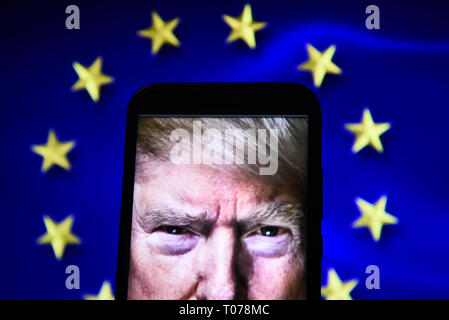 US-Präsident, Donald Trump Augen sind auf ein Android Handy mit Fahne der Europäischen Union auf dem Hintergrund gesehen. Stockfoto