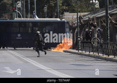 Athen, Griechenland. 18 Mär, 2019. Ein Demonstrant aus dem Schwarzen Block schleudert ein Benzin Bombe bei der Bereitschaftspolizei. Ein paar tausende Schülerinnen und Schüler auf die Straße gingen gegen die anstehenden Reformen in der Bildung, die Sie behaupten, Sie fahren für bezahlte Fortbildung suchen, eine zusätzliche finanzielle Belastung zu ihren Eltern zu demonstrieren. Credit: Nikolas Georgiou/ZUMA Draht/Alamy leben Nachrichten Stockfoto