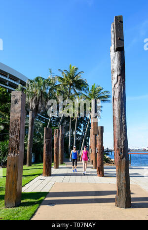 Fußgänger unter Totems, die Vergangenheit der Aborigines leben im Bereich, Marlin Wharf, Cairns, Far North Queensland, FNQ, QLD, Australien Stockfoto