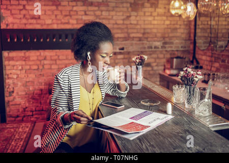 Elegante afroamerikanischen Frau trinkt Kaffee und spiegeln Magazin Mode Stockfoto