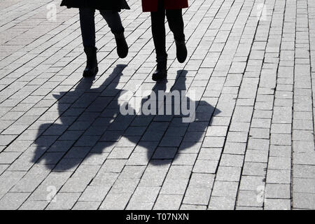 Silhouetten und Schatten der zwei Frauen auf der Straße. Menschen Hand in Hand im Freien, Konzept der Zwillinge, weibliche Freundschaft, Lesben, dramatische Stockfoto