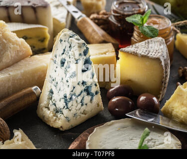 Auswahl an verschiedenen Käsesorten mit Oliven und Marmeladen. Essen Hintergrund. Stockfoto