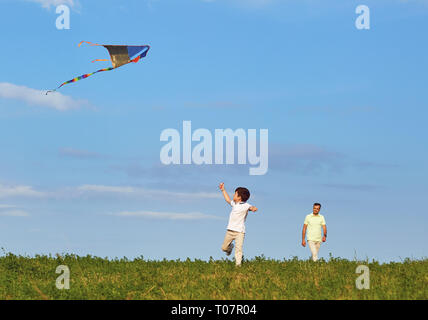 Vater und Sohn spielen mit einem Drachen in der Natur. Stockfoto