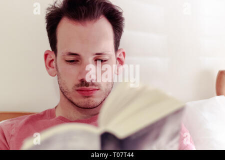 Mann im Bett und liest Buch zu Hause für Konzept verwenden Stockfoto