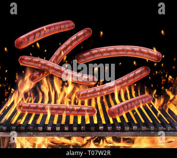 Würstchen fallen auf den brennenden Grill Gitter und Zungen wie von Feuer Flamme. Stockfoto
