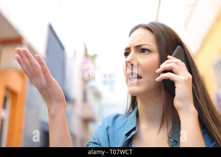 Wütende Frau sprechen über Smart Phone beschweren zu Fuß auf der Straße Stockfoto