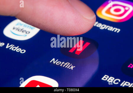 Finger, mit Netflix App auf einem Touchscreen auf einem Tablet-PC oder Handy Gerät. Laden Netflix Anwendung. Netflix Verknüpfung. Stockfoto