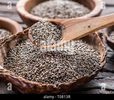 Chia Samen in hölzernen Löffel über organische Gericht mit Chia Samen auf alten Holztisch. Stockfoto