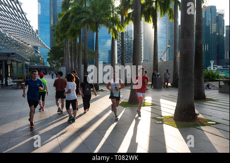 26.12.2018, Singapur, Singapur, Singapur - Jogger Spaziergang entlang der Marina Bay, während im Hintergrund kann man die Wolkenkratzer von Singa Stockfoto