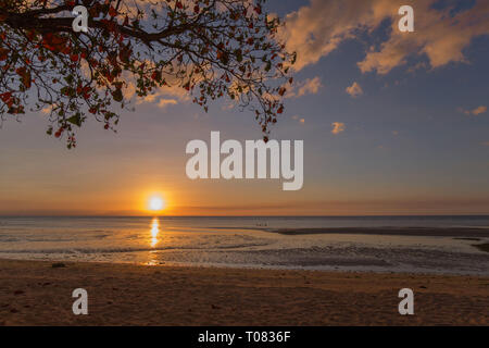 Sonnenuntergang am Strand, eine Niederlassung und Wolken sind farbige und sonnendurchfluteten das Meer bei Ebbe, einem ruhigen Szene in einem Sommerabend Ferienhäuser Stimmung Stockfoto