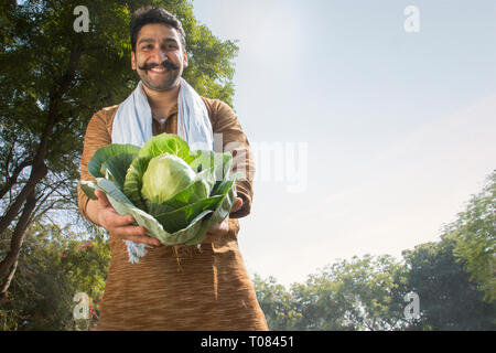 Nahaufnahme eines lächelnden Landwirt oder Dorf Mann mit einem großen Blumenkohl. Stockfoto