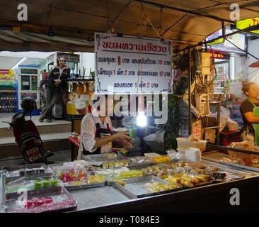 CHIANG MAI, THAILAND – 2018. MÄRZ: Eine Frau zeigt Thai-Lebensmittel zum Verkauf auf dem Nachtmarkt in Chiang Mai. Stockfoto