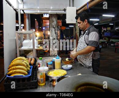 CHIANG MAI, THAILAND – 2018. MÄRZ: Ein Mann bereitet auf dem Nachtmarkt in Chiang Mai eine thailändische Delikatesse zum Verkauf vor. Stockfoto