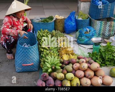 CAN THO, VIETNAM – 2018. MÄRZ: Eine weibliche Straßenverkäuferin verkauft auf dem Cho an Binh-Markt verschiedene Obst- und Gemüsesorten. Stockfoto