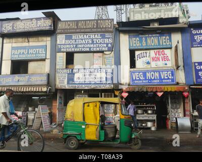NEU-DELHI, INDIEN – 2018. MÄRZ: Riesige Schilder vor den Unternehmen in Neu-Delhi, mit einem Auto und einer Fahrrad-Rikscha vor dem Hotel. Stockfoto