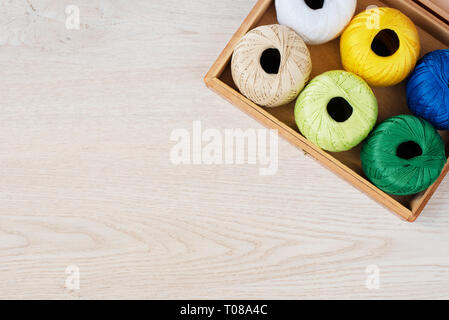 Set aus bunten Fäden für Stricken, Häkeln in Holzkiste, die auf dem Tisch Stockfoto