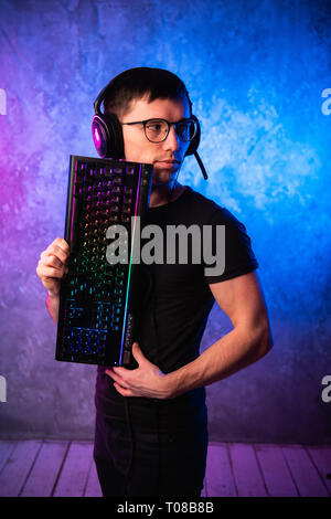 Professionelle boy Gamer, Gaming Keyboard über bunte Rosa und Blau Neon beleuchtete Wand. Gaming gamer Konzept Stockfoto