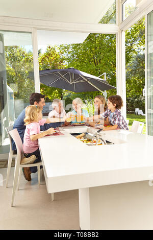 Große Familie am Tisch sitzt mit Mittagessen und Toasten mit Saft Stockfoto