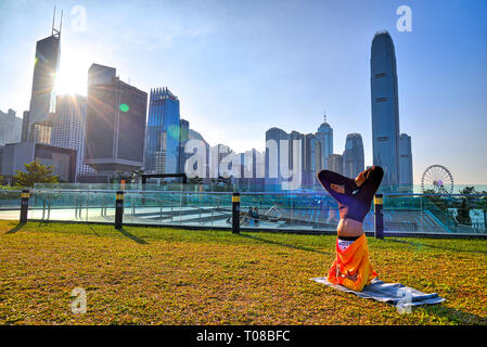 Lifestyle in Hong Kong - Frauen praktizieren Yoga im Park mit Stadtbild Hintergrund Stockfoto