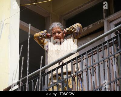 MANALI, HIMACHAL PRADESH, INDIEN – 2018. MÄRZ: Eine Frau blickt vom Balkon eines dritten Gebäudes in der Resortstadt Manali herunter. Stockfoto