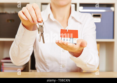 Broker hält ein kleines Haus und Schlüssel in der Hand Stockfoto