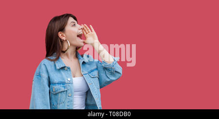 Profil Seitenansicht Portrait von schreienden schöne Brünette junge Frau mit Make-up in Denim lässige Form mit Hand, schrie copyspace Wal Stockfoto