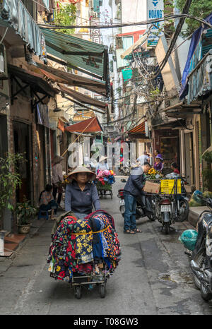 Ein straßenhändler mit hand Barrow in Hanoi verkaufen Tuch Stockfoto