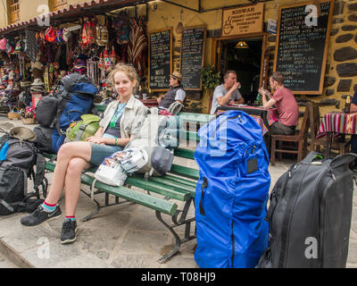 Cusco, Peru - 20. Mai 2016: Junge Frau sitzt auf der Bank und sieht für das Reisegepäck während der Reise zum Machu Picchu. Südamerika. Stockfoto