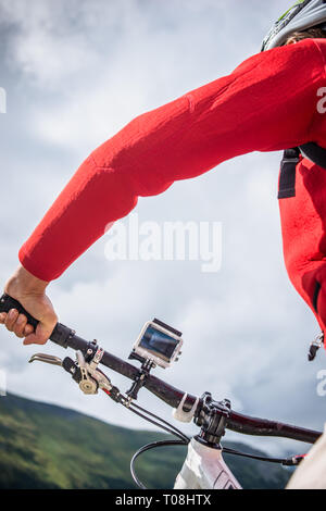 Junge Frau auf Mountainbike mit action video Kamera ausgestattet. Schuß an Furker Pass, Schweizer Alpen, im Sommer. Stockfoto