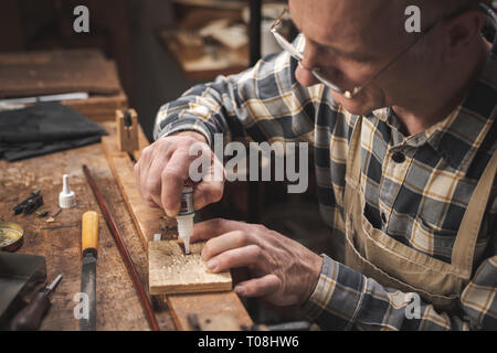 Reifen artisan in einer rustikalen Umgebung sitzen, während sorgfältig Auftragen von Leim auf einer kleinen Los Stockfoto