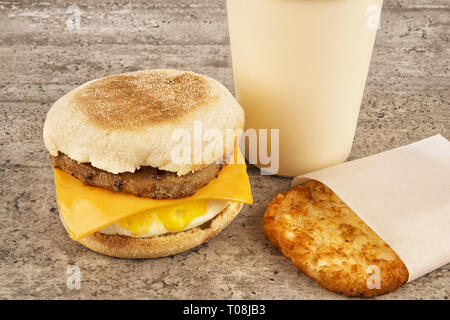 Breakfast Sandwich mit Kaffee und Hash Brown auf konkrete Tabelle. Englische Muffins, Ei, Käse und Wurst. Stockfoto