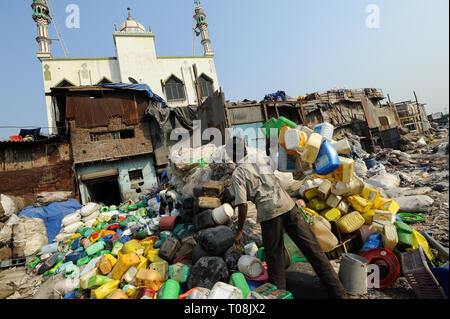 07.12.2011, Mumbai, Maharashtra, Indien - ein Mann sortiert Kunststoff Behälter für das Recycling in Mumbai die Dharavi Armenviertel mit Moinia Masjid im Hintergrund, D Stockfoto