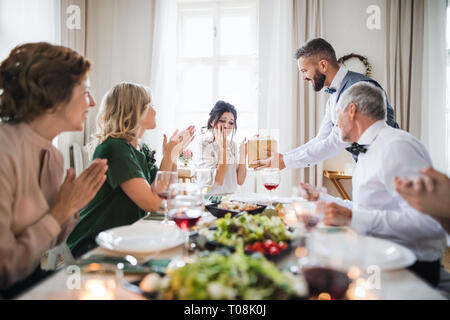 Ein Mann, der ein Geschenk überrascht junge Frau auf einer Geburtstagsfeier in der Familie. Stockfoto