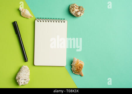 Sommerferien flach Konzept mit Stift und Notizblock und ein paar Muscheln auf Pastell trendy blau-grünem Hintergrund. Ansicht von oben. Stockfoto