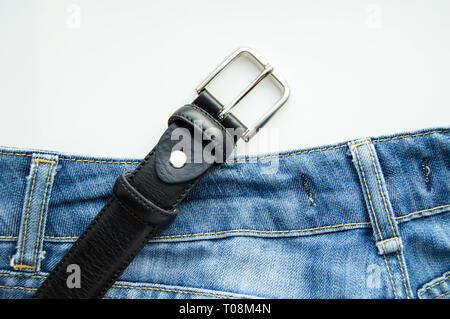 Blaue Jeans und schwarzem Lederband auf weißem Hintergrund, lässige Kleidung für Männer. Stockfoto