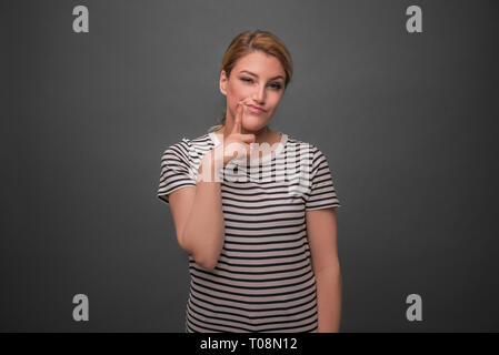 Junge Frau denken auf einem grauen Hintergrund. Stockfoto