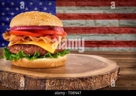 Cheeseburger mit Speck. Der USA-Flagge auf der Mauer im Hintergrund. Stockfoto