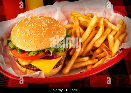 Burger und Pommes frites in Korb auf tartan Tischdecke. Ketchup und Senf Flasche im Hintergrund. Close Up. Stockfoto