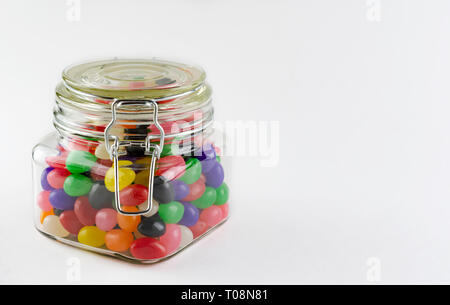 Ein Sortiment von Jelly Beans in einem Glas mit Verschluss deckel. Auf weissem Hintergrund. Kopieren Raum auf der rechten Seite. Stockfoto