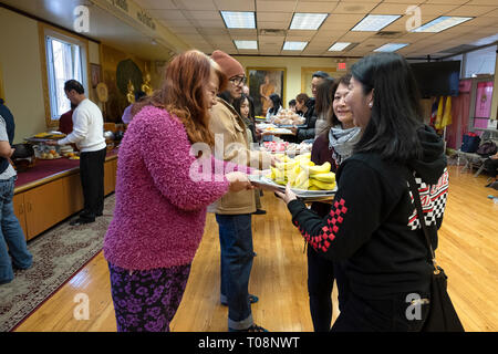 Anbeter in einem buddhistischen Tempel Form einer Montagelinie zu dienen Essen, besonders für ihre Mönche vorbereitet. In Elmhurst, Queens, New York City. Stockfoto