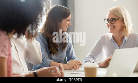 Freundlich lächelnden Alte und junge Unternehmerinnen Reden in der Sitzung lachen Stockfoto